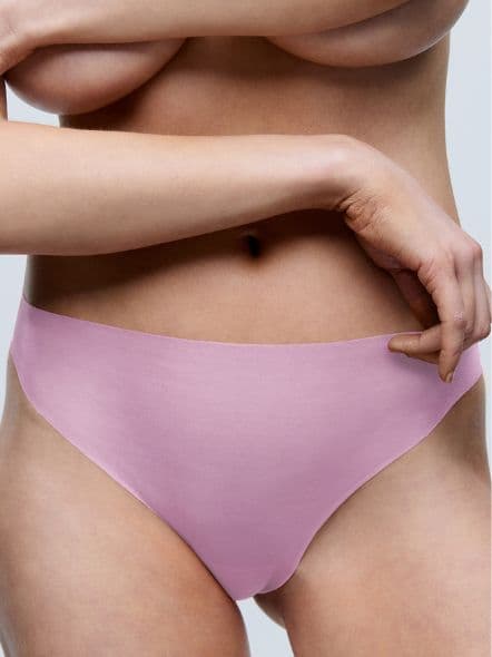 A person wearing pink seamless underwear, showing a close-up of the lower torso and part of a hand against a neutral background.