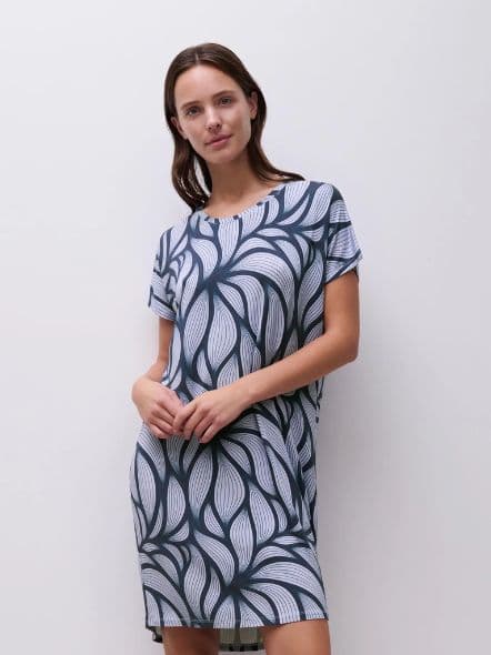 Woman wearing a short-sleeved, leaf-patterned dress with a relaxed fit, standing against a plain white background.